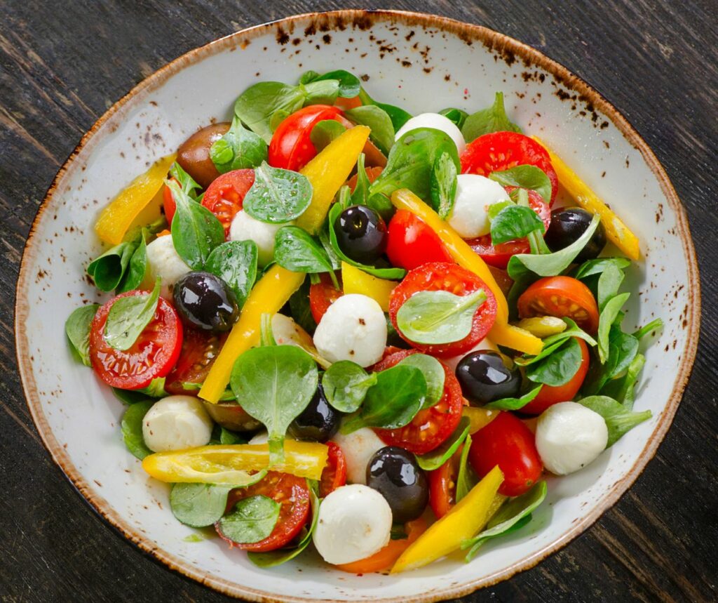 Ensalada de tomates, pimientos, aceitunas y mozzarella con bocados de heura a la plancha