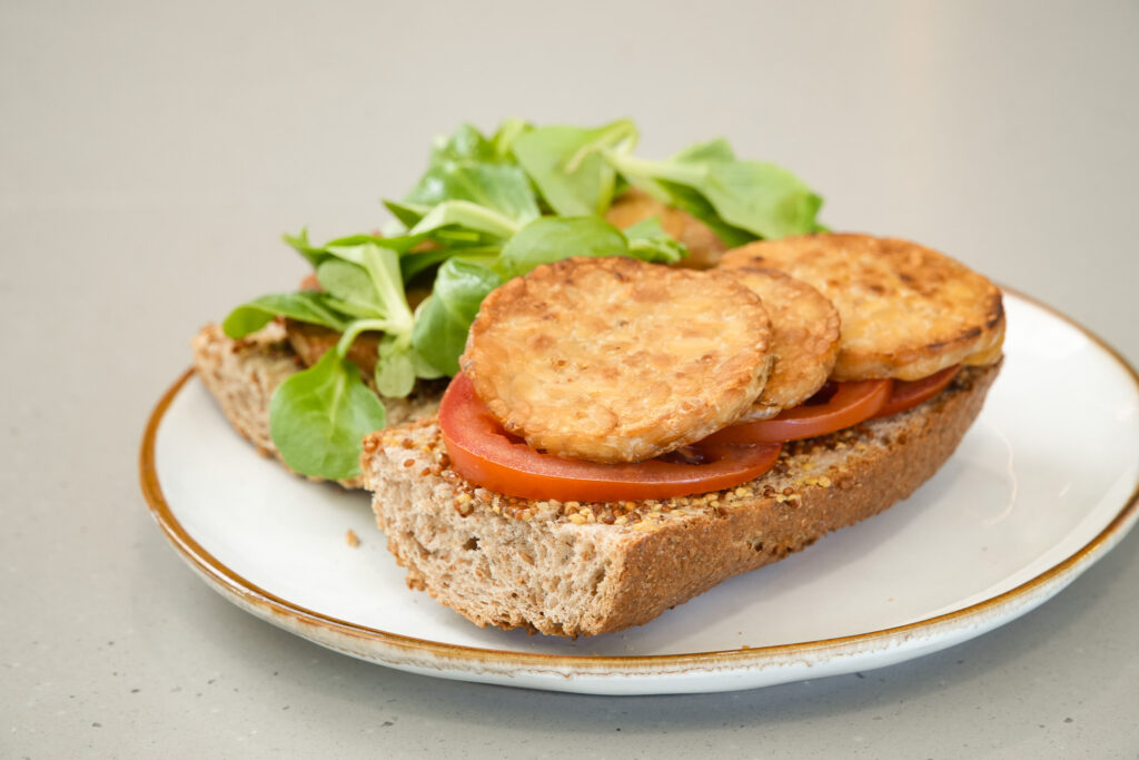 Bocadillo con mostaza, tempeh, tomate y canónigos